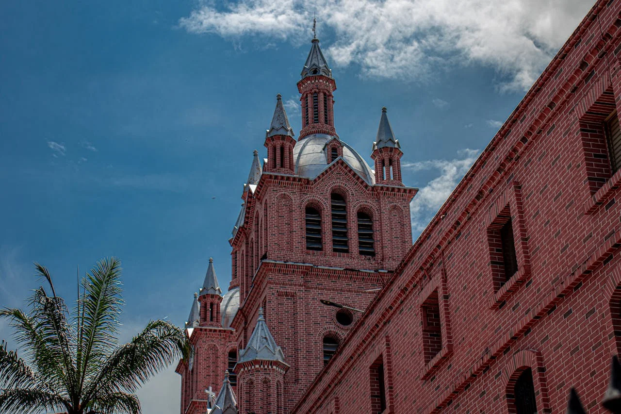 Basílica del Señor de los Milagros en Buga, Colombia, con arquitectura de ladrillo y cielo azul.